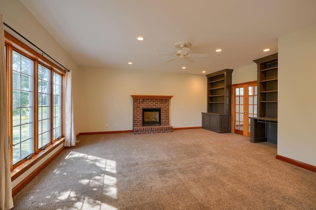 unfurnished living room with light carpet, ceiling fan, a healthy amount of sunlight, and a brick fireplace