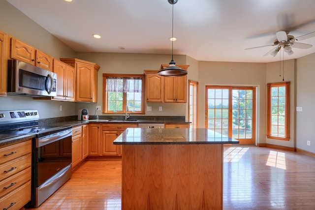 kitchen with a center island, light hardwood / wood-style flooring, a healthy amount of sunlight, and appliances with stainless steel finishes