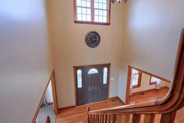 entrance foyer with a towering ceiling and light hardwood / wood-style flooring