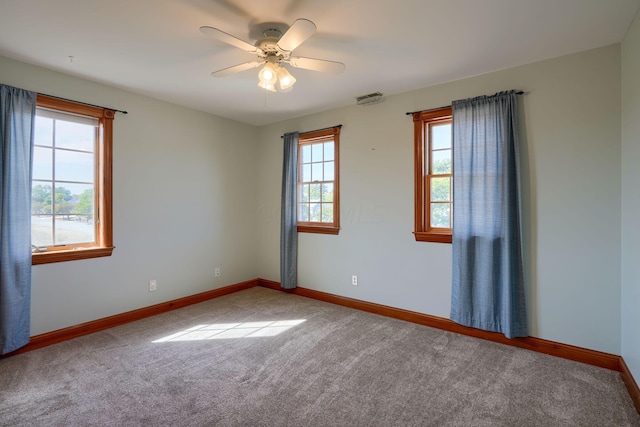 carpeted empty room with ceiling fan and a healthy amount of sunlight