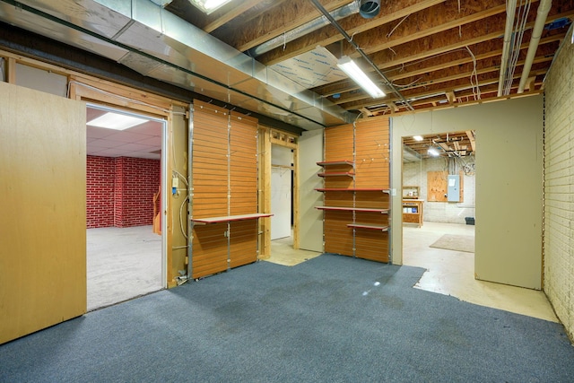 basement featuring electric panel and brick wall