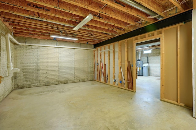 basement with gas water heater and brick wall