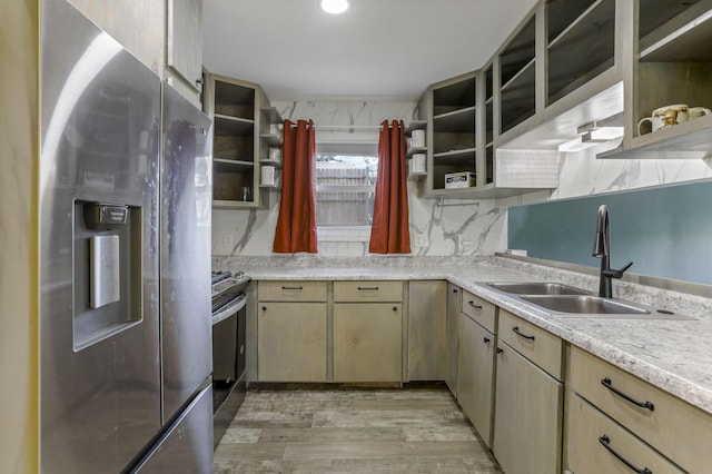 kitchen with appliances with stainless steel finishes, backsplash, sink, light brown cabinets, and light hardwood / wood-style floors