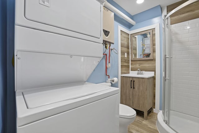 bathroom with hardwood / wood-style floors, vanity, a shower with door, stacked washer and clothes dryer, and toilet