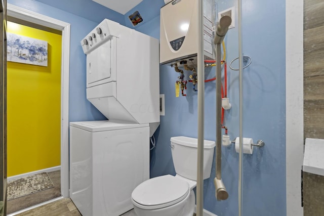 bathroom featuring toilet, wood-type flooring, and stacked washing maching and dryer