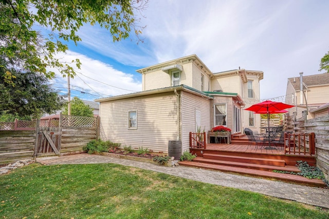 rear view of house with a lawn and a wooden deck