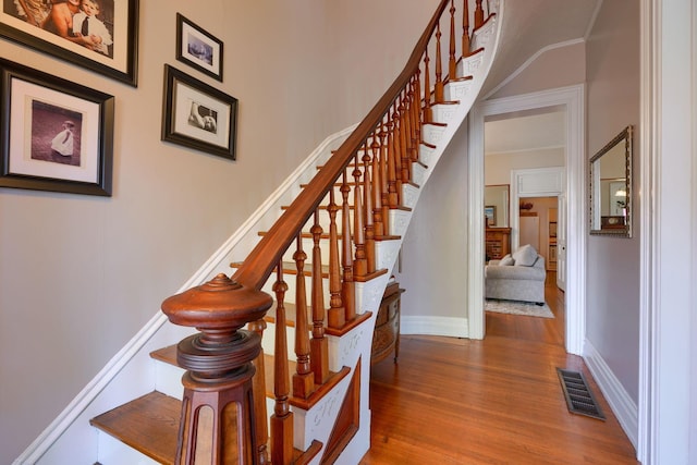 staircase with a fireplace and hardwood / wood-style floors