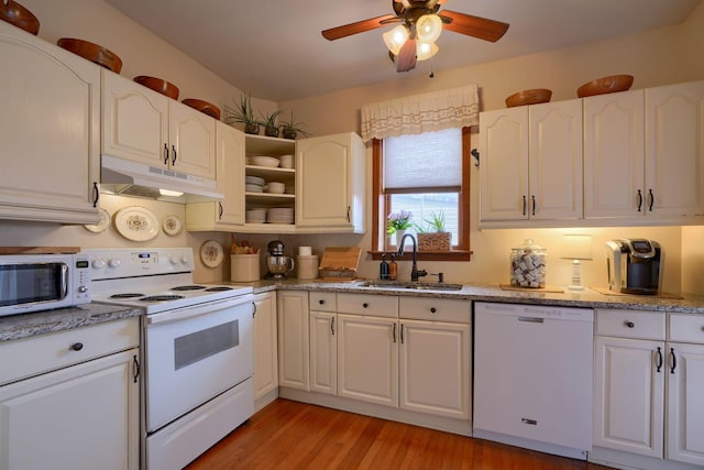 kitchen with white appliances, white cabinets, sink, light hardwood / wood-style flooring, and light stone countertops