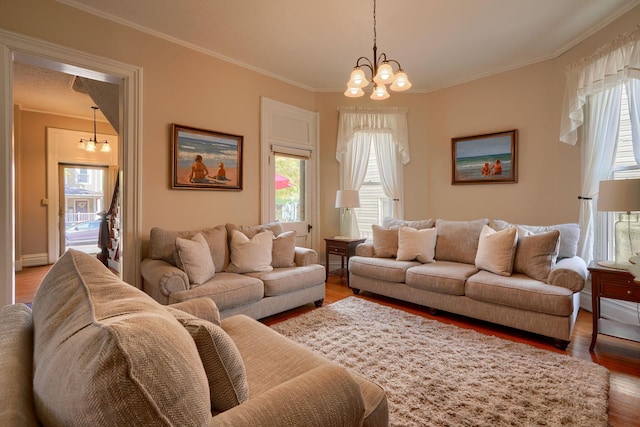 living room featuring ornamental molding, wood-type flooring, and an inviting chandelier