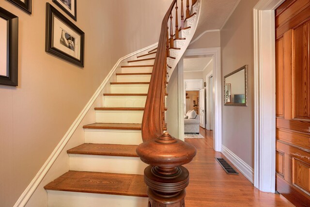 staircase with crown molding and hardwood / wood-style floors