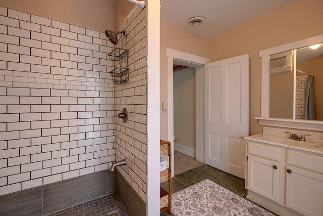 bathroom featuring tile patterned floors, vanity, and a tile shower