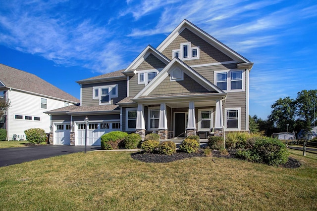 craftsman house with covered porch, a front yard, and a garage