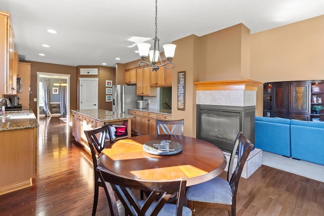 dining space with a fireplace, sink, dark wood-type flooring, and a chandelier