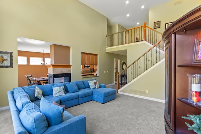 living room featuring a tile fireplace, a towering ceiling, and carpet floors