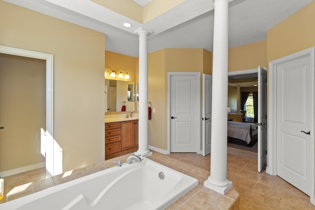 bathroom featuring a tub to relax in, ornate columns, tile patterned flooring, and vanity