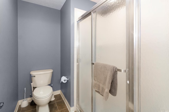 bathroom featuring toilet, tile patterned floors, and a shower with door