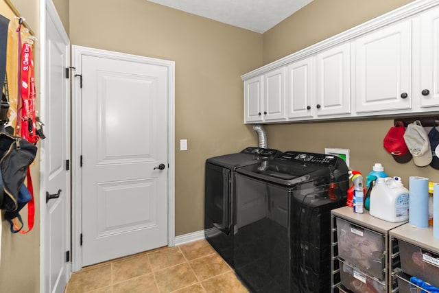 clothes washing area with cabinets, washing machine and dryer, and light tile patterned flooring