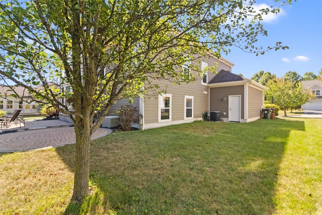 rear view of property featuring a lawn and central AC unit