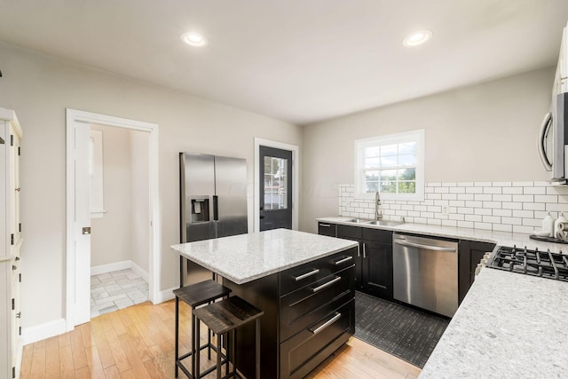 kitchen with sink, a breakfast bar area, light hardwood / wood-style flooring, a kitchen island, and stainless steel appliances