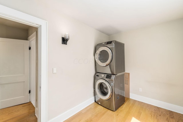 clothes washing area featuring hardwood / wood-style floors and stacked washing maching and dryer