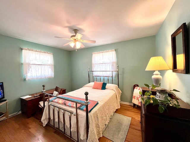 bedroom featuring hardwood / wood-style floors, ceiling fan, and multiple windows