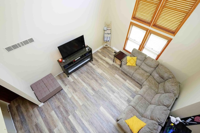 living room featuring a towering ceiling and light wood-type flooring