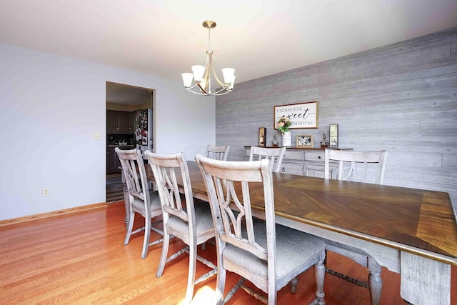 dining space with light wood-type flooring and an inviting chandelier