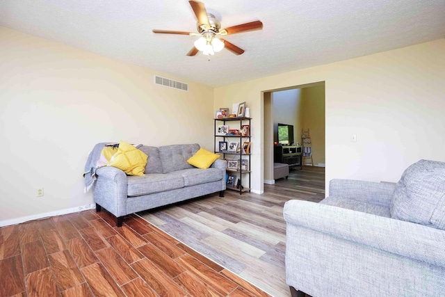 living room featuring wood-type flooring, a textured ceiling, and ceiling fan