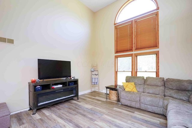 living room with light hardwood / wood-style floors and a high ceiling