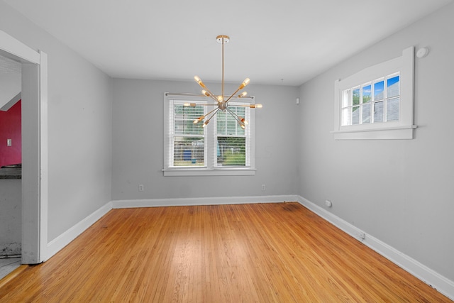 unfurnished dining area with a chandelier and light hardwood / wood-style floors