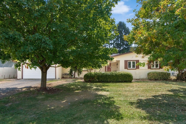 view of property hidden behind natural elements featuring a garage and a front lawn