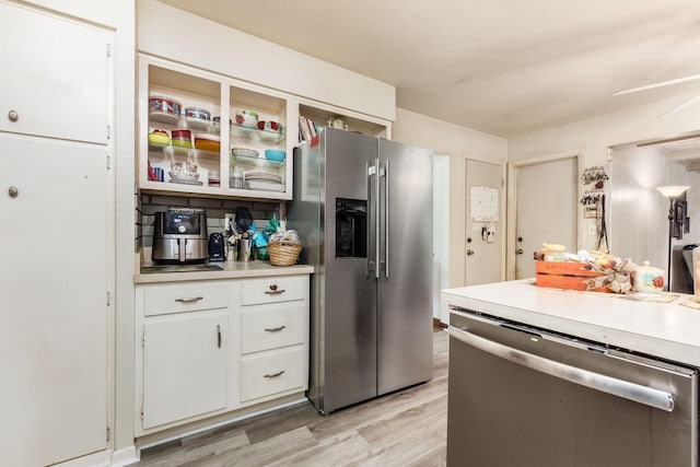 kitchen with stainless steel appliances, white cabinetry, and light hardwood / wood-style floors