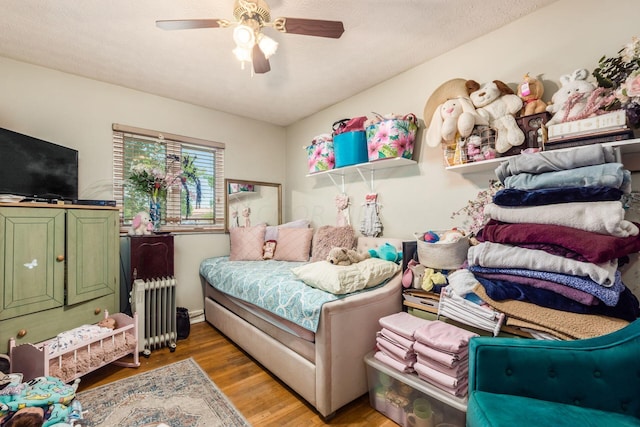 bedroom with hardwood / wood-style flooring, ceiling fan, a textured ceiling, and radiator