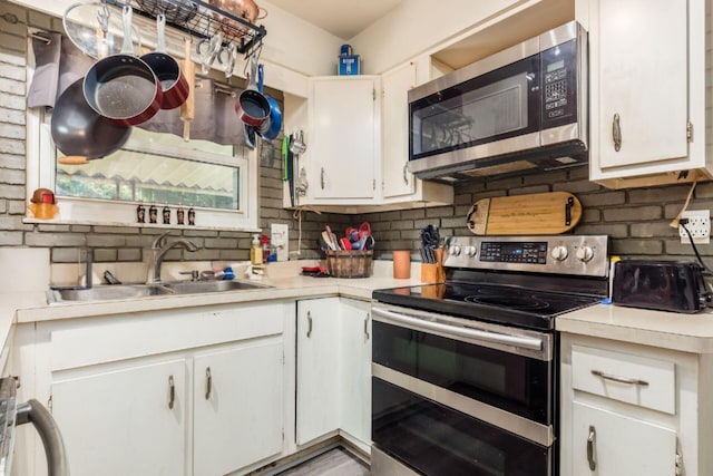 kitchen featuring white cabinets, sink, stainless steel appliances, and tasteful backsplash