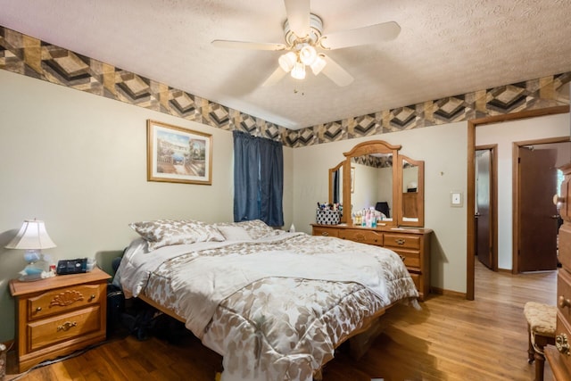 bedroom featuring ceiling fan, light hardwood / wood-style floors, and a textured ceiling