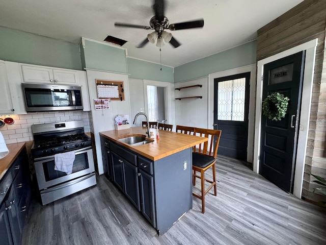 kitchen featuring white cabinets, appliances with stainless steel finishes, blue cabinets, and butcher block counters