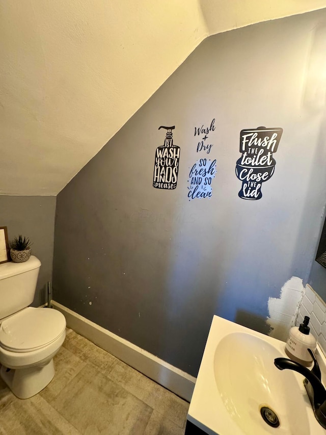 bathroom with vanity, lofted ceiling, and toilet