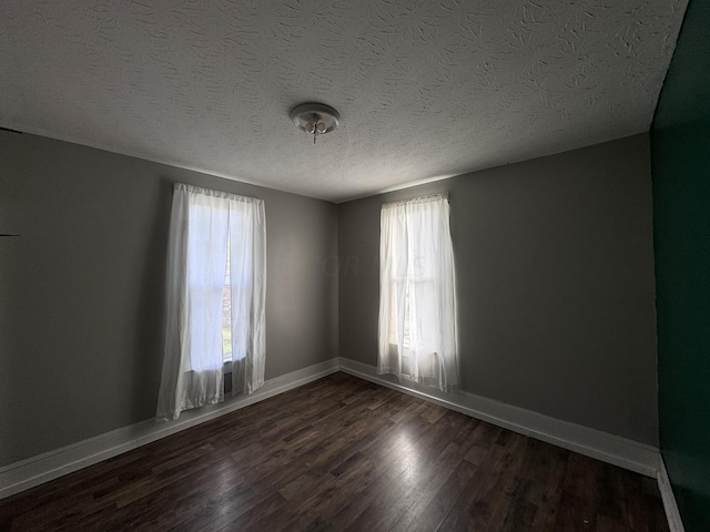 empty room with a textured ceiling and dark hardwood / wood-style flooring