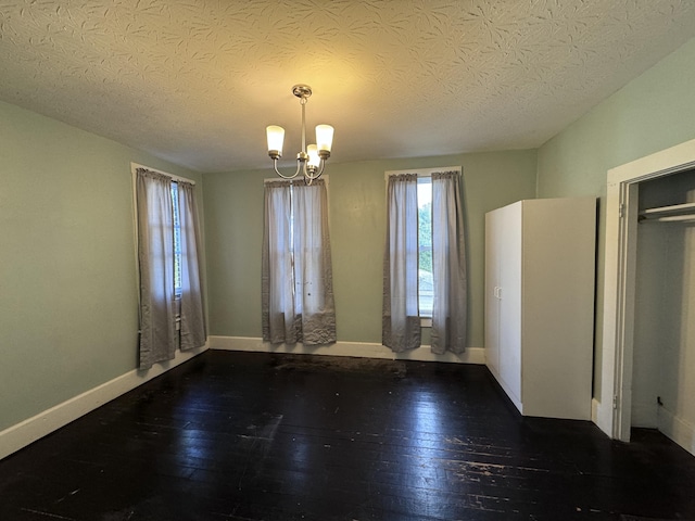 spare room featuring dark hardwood / wood-style flooring, a chandelier, and a textured ceiling