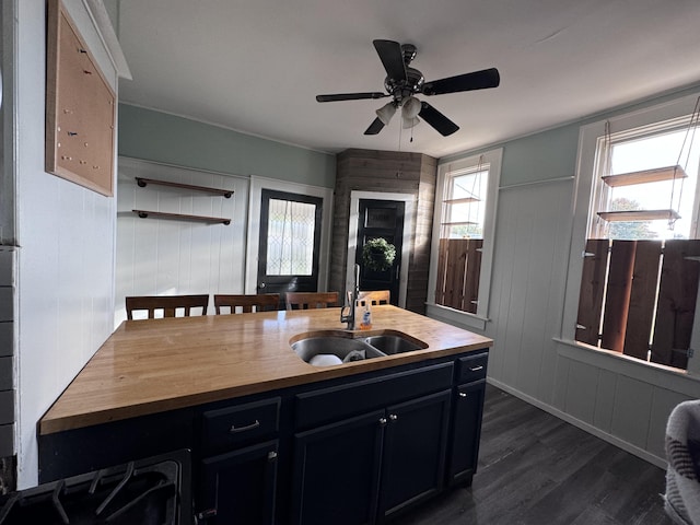 kitchen featuring ceiling fan, sink, wood counters, dark hardwood / wood-style floors, and wood walls