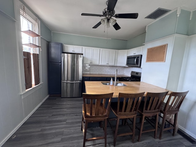 kitchen with white cabinets, tasteful backsplash, stainless steel appliances, and dark wood-type flooring