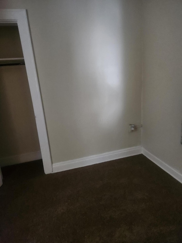 unfurnished bedroom featuring a closet and dark carpet