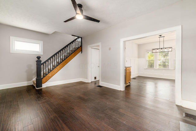 unfurnished living room with a textured ceiling, ceiling fan, and dark wood-type flooring