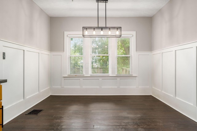 unfurnished dining area featuring dark hardwood / wood-style flooring and a textured ceiling