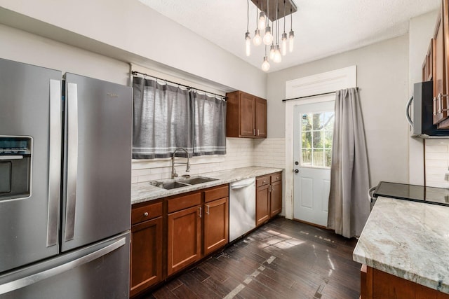 kitchen featuring pendant lighting, sink, decorative backsplash, light stone countertops, and stainless steel appliances