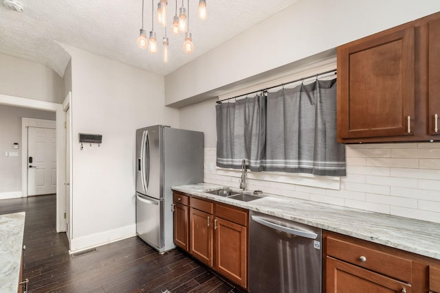 kitchen featuring sink, dark hardwood / wood-style floors, a textured ceiling, decorative light fixtures, and stainless steel appliances