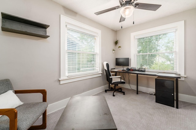 carpeted home office with ceiling fan and a wealth of natural light