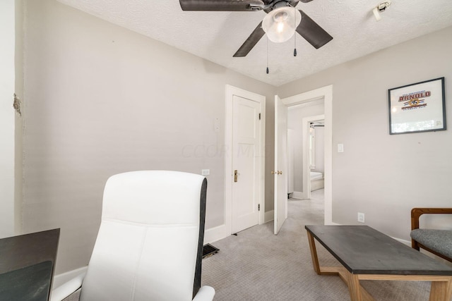 carpeted office featuring a textured ceiling and ceiling fan