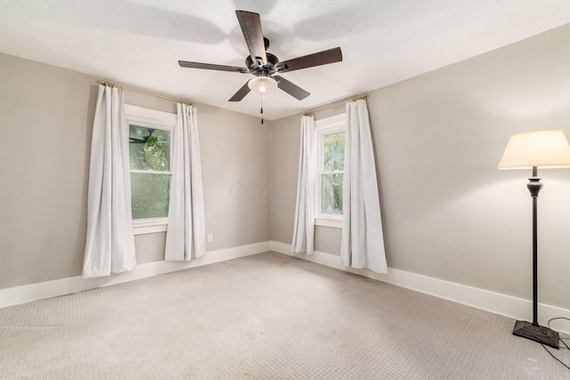 empty room featuring ceiling fan, light colored carpet, a healthy amount of sunlight, and a textured ceiling