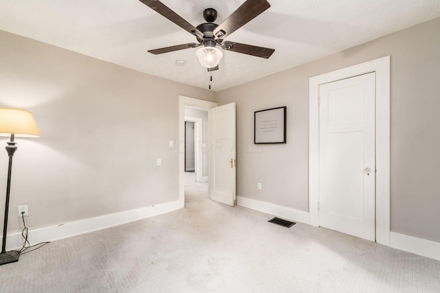 unfurnished bedroom with light carpet, a textured ceiling, and ceiling fan